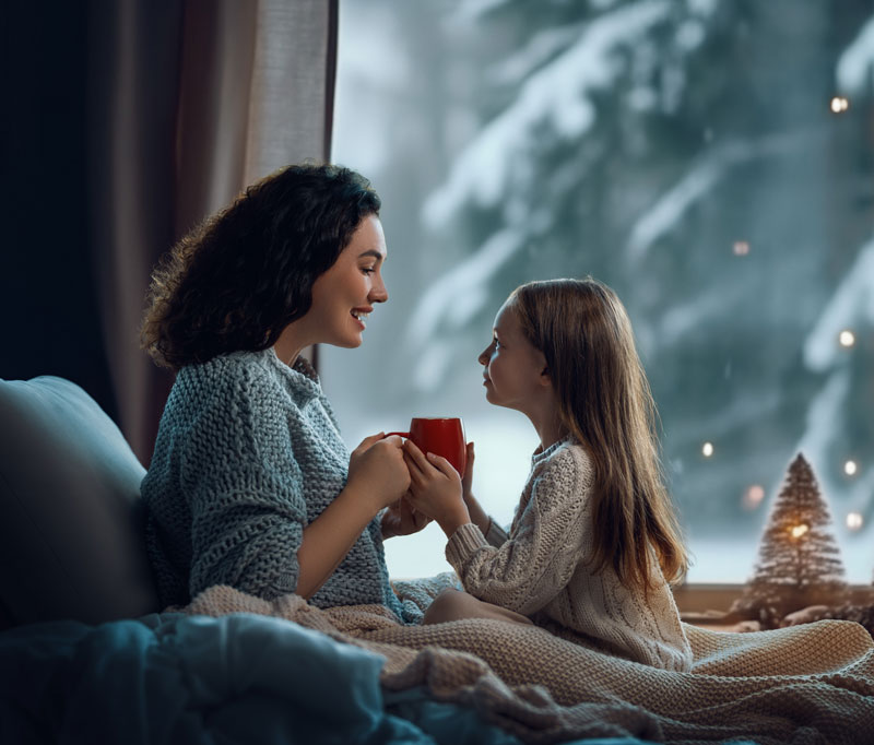 Mother and daughter talking and smiling enjoying warm home in the winter